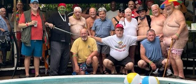 Friends in swimwear gathered poolside under umbrellas